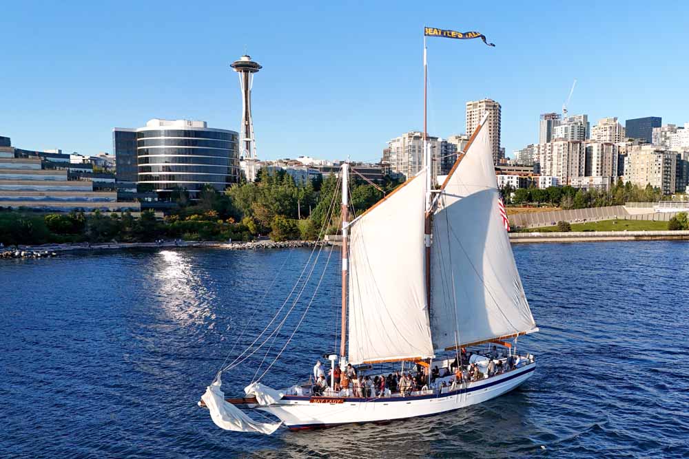 World Cup viewing spots Seattle. The Bay Lady tall ship under full sail on Elliott Bay, with the Seattle waterfront and Space Needle visible in the background.