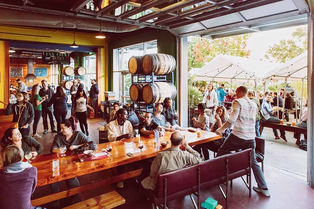 Seattle soccer bars World Cup 2026. Fremont Brewing taproom packed with guests on a summer day, roll-top doors open to the street.