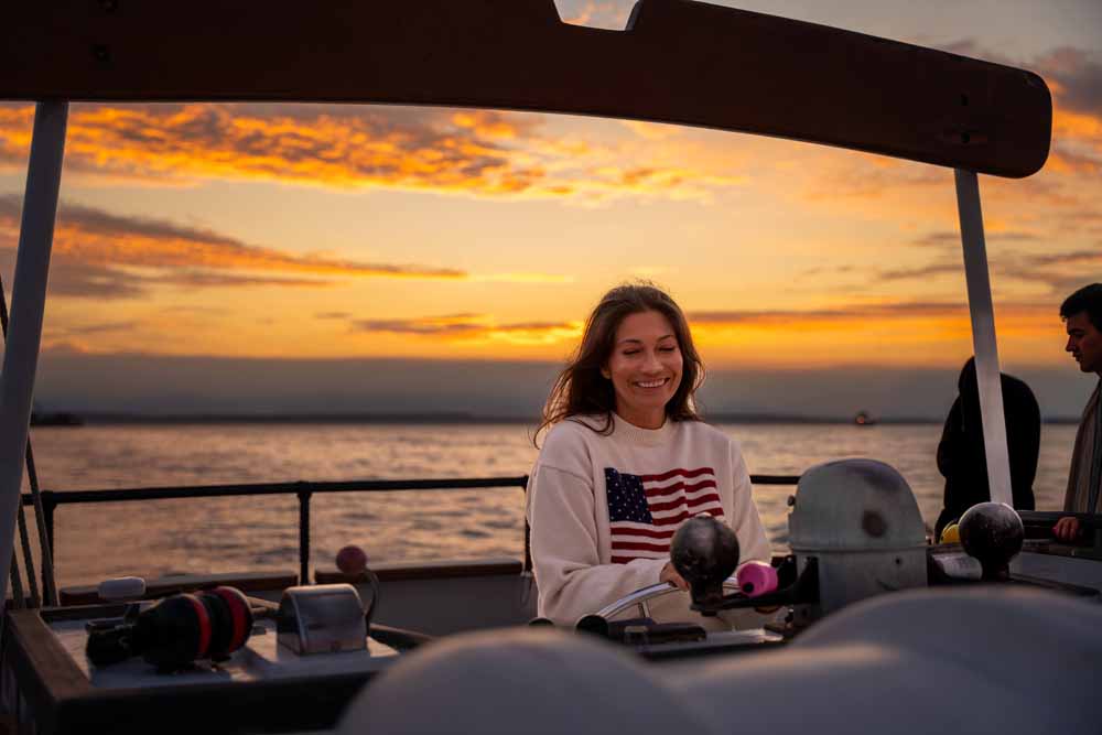 Seattle waterfront activities World Cup. A woman takes a turn at the helm of the Bay Lady tall ship on a public sunset sail on Elliott Bay.