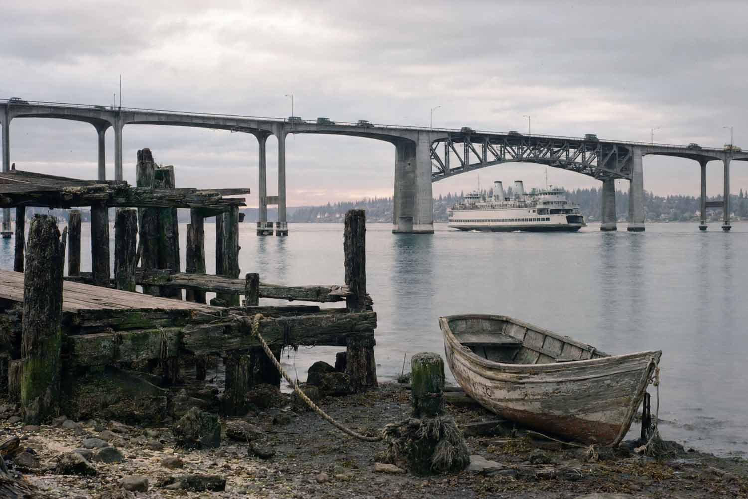 Puget Sound maritime history. A bridge spanning Seattle's shipping canal, marking the shift from small independent boats to fixed roads.