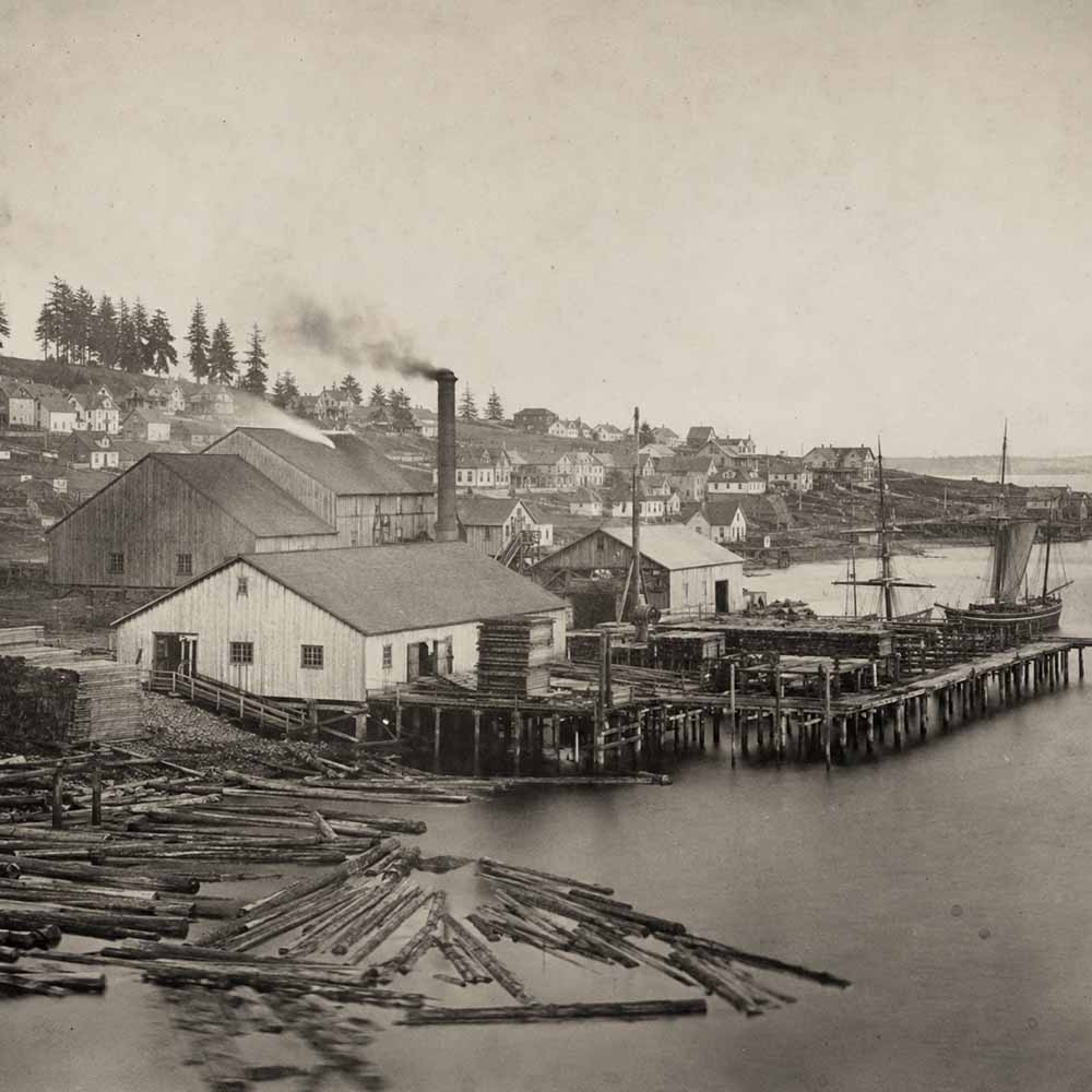 Origin of skid row. Logs and stacked lumber along Henry Yesler's waterfront sawmill in 1850s Seattle.